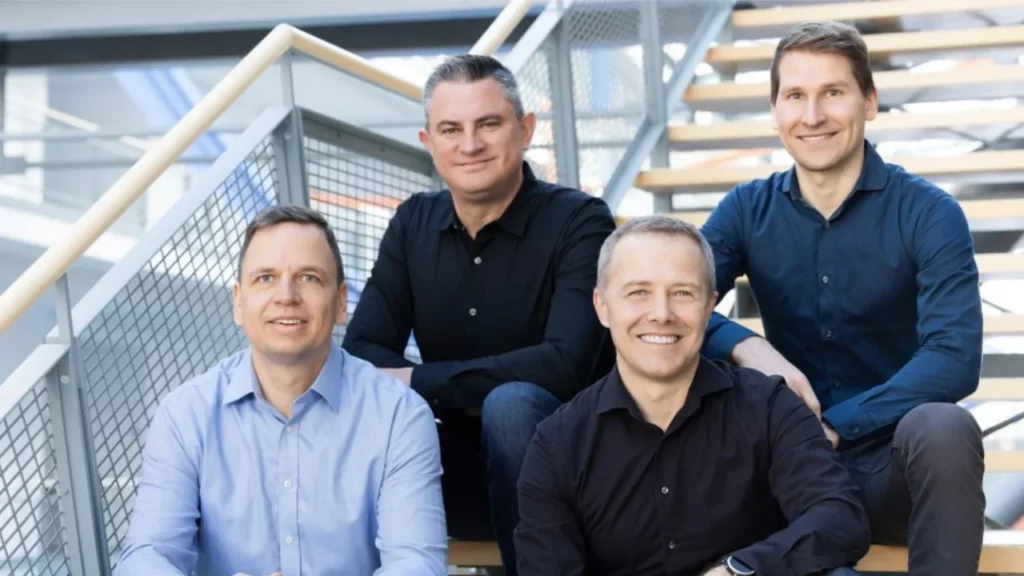 Portrait of four men sitting on a staircase, smiling.